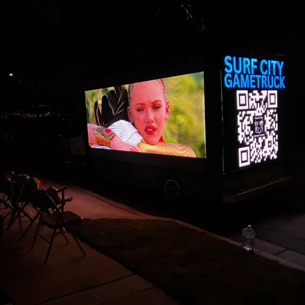 The LED movie truck screening a film at night with families watching from camp chairs