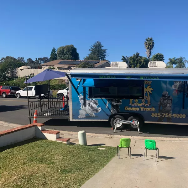 The game truck parked on a residential street in daylight with the outside gaming stage set up