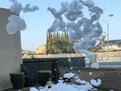 A back yard filling with foam from the foam cannon while a child runs through it laughing